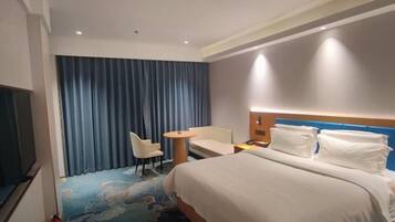 Una habitación de hotel con cama, televisión, escritorio y silla.