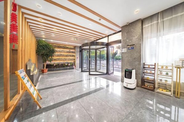 A modern hotel lobby with a rotating door, a digital information kiosk, and a reception desk. - Kaiyuan M Hotel (Shaoxing Keqiao Linglong Branch) (Shaoxing)