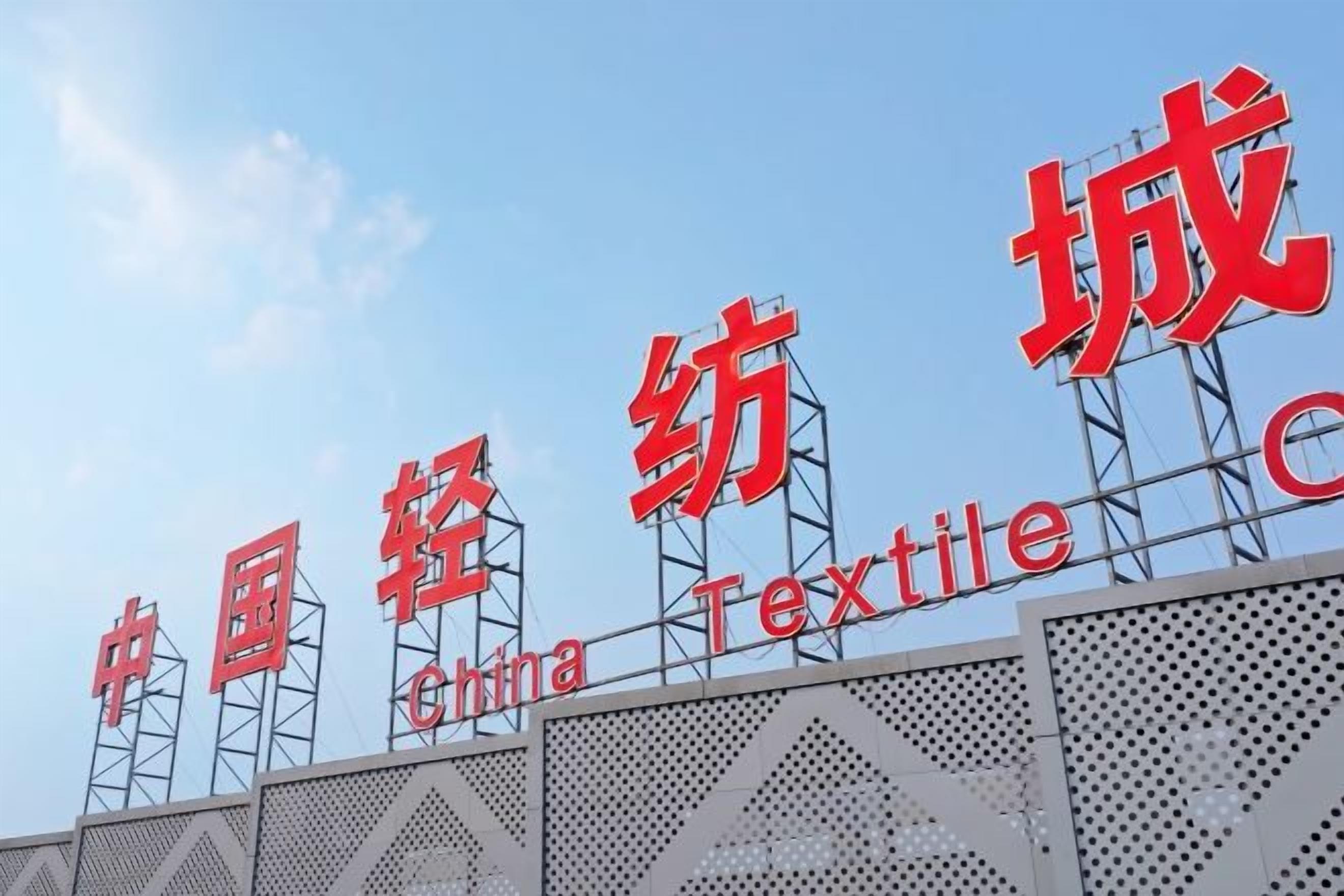 Une enseigne avec l’inscription « China Textile » en lettres rouges, fixée sur une structure métallique.