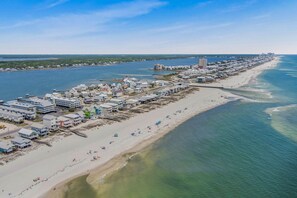 Vista aérea de un pueblo costero con una extensa playa, edificios y un puerto deportivo.