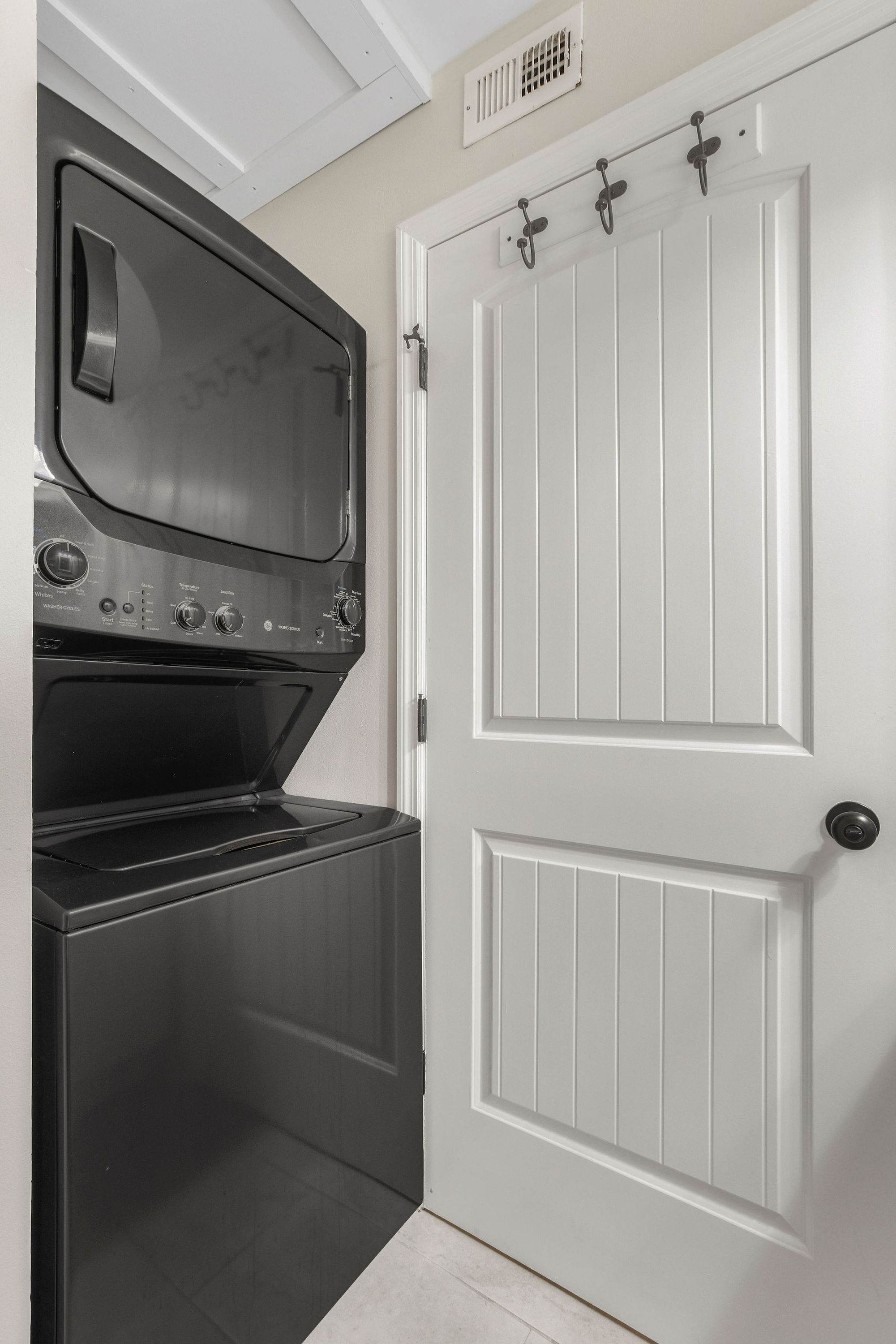 A laundry room with a washer and dryer, a white door with a handle, and a vent above the door.