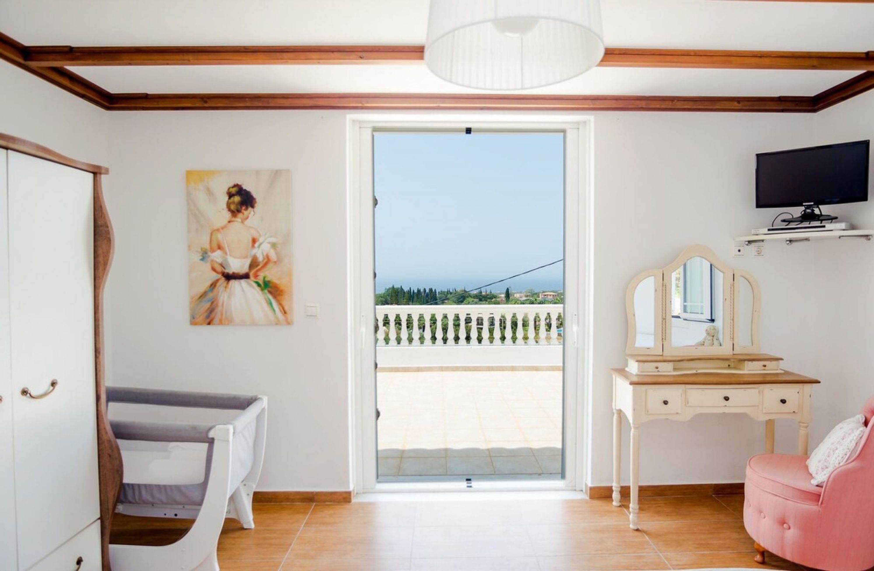 Une chambre avec un balcon, un tableau, une télévision et un bureau.