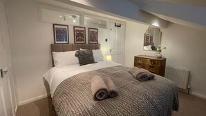 Una camera da letto con un letto grande, una cassettiera, uno specchio e quadri appesi al muro.