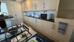 Una cucina moderna con piano cottura a gas, forno a microonde e pensili bianchi.
