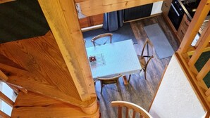 Un escalier en colimaçon en bois menant à une pièce où se trouvent une table et des chaises.