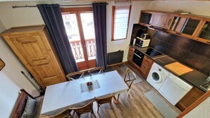 Une cuisine compacte comprenant une table à manger, des chaises, un lave-linge et un four à micro-ondes.