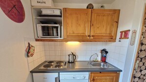 A compact kitchen with wooden cabinets, a microwave, a dishwasher, and a sink. - 100m from ski slopes, 2nd floor, balcony, ski locker, 36m², Valfréjus (Valfréjus)