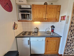 A compact kitchen with wooden cabinets, a microwave, a dishwasher, and a sink. - 100m from ski slopes, 2nd floor, balcony, ski locker, 36m², Valfréjus (Valfréjus)
