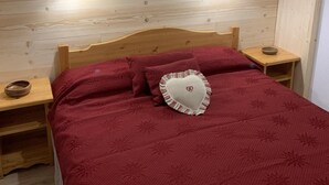 A wooden bedroom with a bed, nightstands, and a shelf with decorative items. - 100m from ski slopes, 2nd floor, balcony, ski locker, 36m², Valfréjus (Valfréjus)