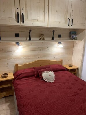 A wooden bedroom with a bed, nightstands, and a shelf with decorative items. - 100m from ski slopes, 2nd floor, balcony, ski locker, 36m², Valfréjus (Valfréjus)