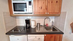 A compact kitchen with wooden cabinets, a microwave, a coffee maker, a dishwasher, and a sink. - 50m from ski slopes, 2nd floor, view mountain, balcony, tv, ski locker, 23m², Valfréjus (Valfréjus)