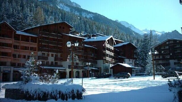 A snow-covered mountain resort with wooden buildings and a clear view of the mountains. - 50m from ski slopes, 2nd floor, view mountain, balcony, tv, ski locker, 23m², Valfréjus (Valfréjus)
