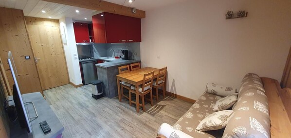 A compact living space with a kitchenette, a dining area, and a sofa.