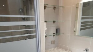 A modern bathroom with a glass shower enclosure, a white sink, and a mirror.