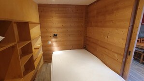 A small, compact room with a wooden bunk bed and a single bed.