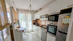 A modern kitchen with white cabinets, a built-in oven, and a refrigerator.