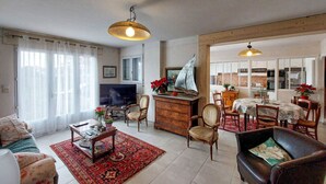 A living room with a television, wooden furniture, and a red patterned rug.