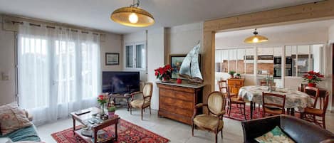 A living room with a television, wooden furniture, and a red patterned rug.