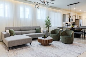 Uma sala de estar moderna com um sofá modular, uma mesa de centro redonda e duas poltronas.