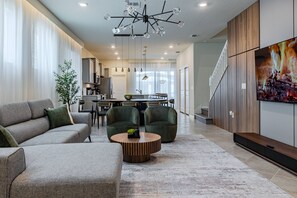 A modern living room with a sofa, chairs, a coffee table, and a TV.