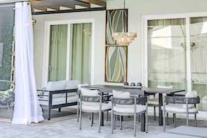 A patio area with a dining table, chairs, and a hanging light fixture.