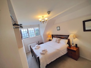 Een slaapkamer met een bed, een bedlampje en een raam.