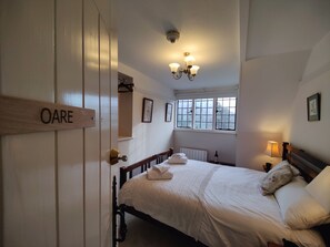 Un dormitorio con cama, una mesita de noche, una lámpara, una ventana y una puerta con la etiqueta 'OARE'.