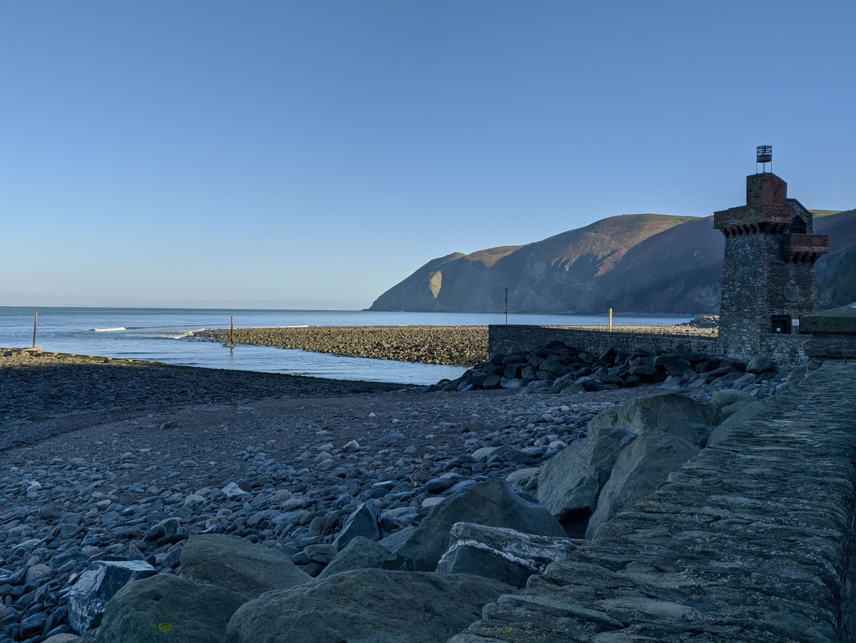Une plage rocheuse avec une structure en pierre et un drapeau au sommet.