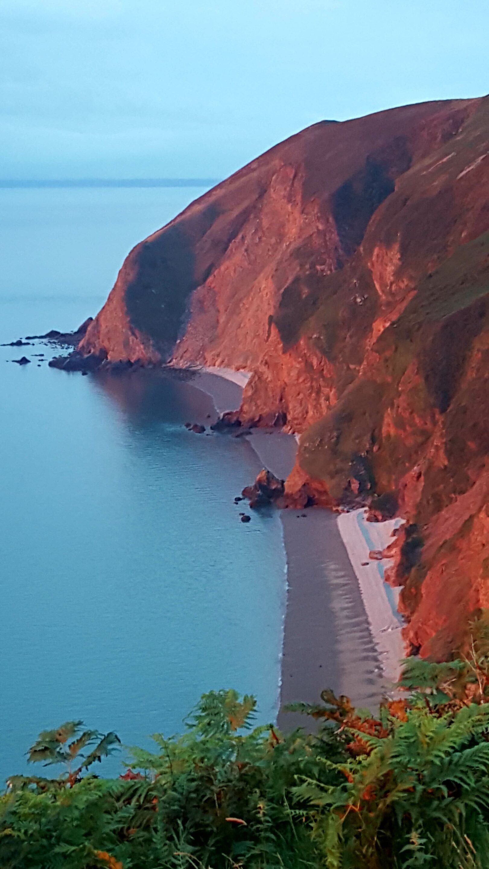 A coastal landscape with a sandy beach and rocky cliffs.