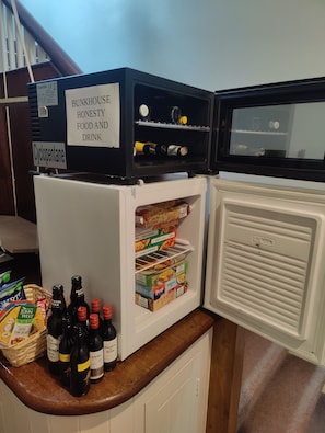 Een keuken met een koelkast en een vrieskast, gevuld met etenswaren en drankjes.
