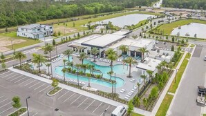 Een modern hotel met een zwembad, parkeerplaats en omliggend groen.