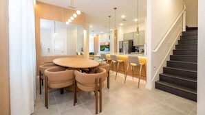 Een moderne keuken met een centraal eiland, een eethoek met een ronde tafel en een trap.