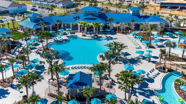 Ein Resort mit einem zentralen Schwimmbad, mehreren Liegebereichen und Palmen.