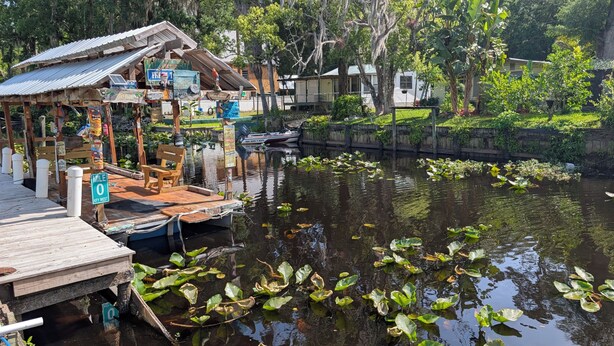 A dock with a wooden bench, a small boat, and a sign indicating 'Mile 0 Key West'.