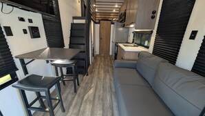Une petite cuisine équipée avec une table et des tabourets, un canapé et un coin repas.