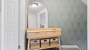 Une coiffeuse en bois, dotée d’un miroir et de trois paniers en osier placés en dessous.