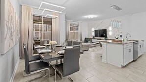 A modern kitchen with white cabinets, a central island, and a built-in oven.