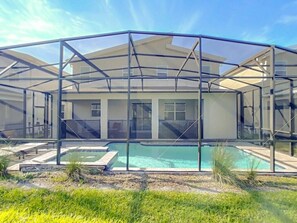 Een modern huis met een zwembad, overdekt terras en een grote glazen uitbouw.