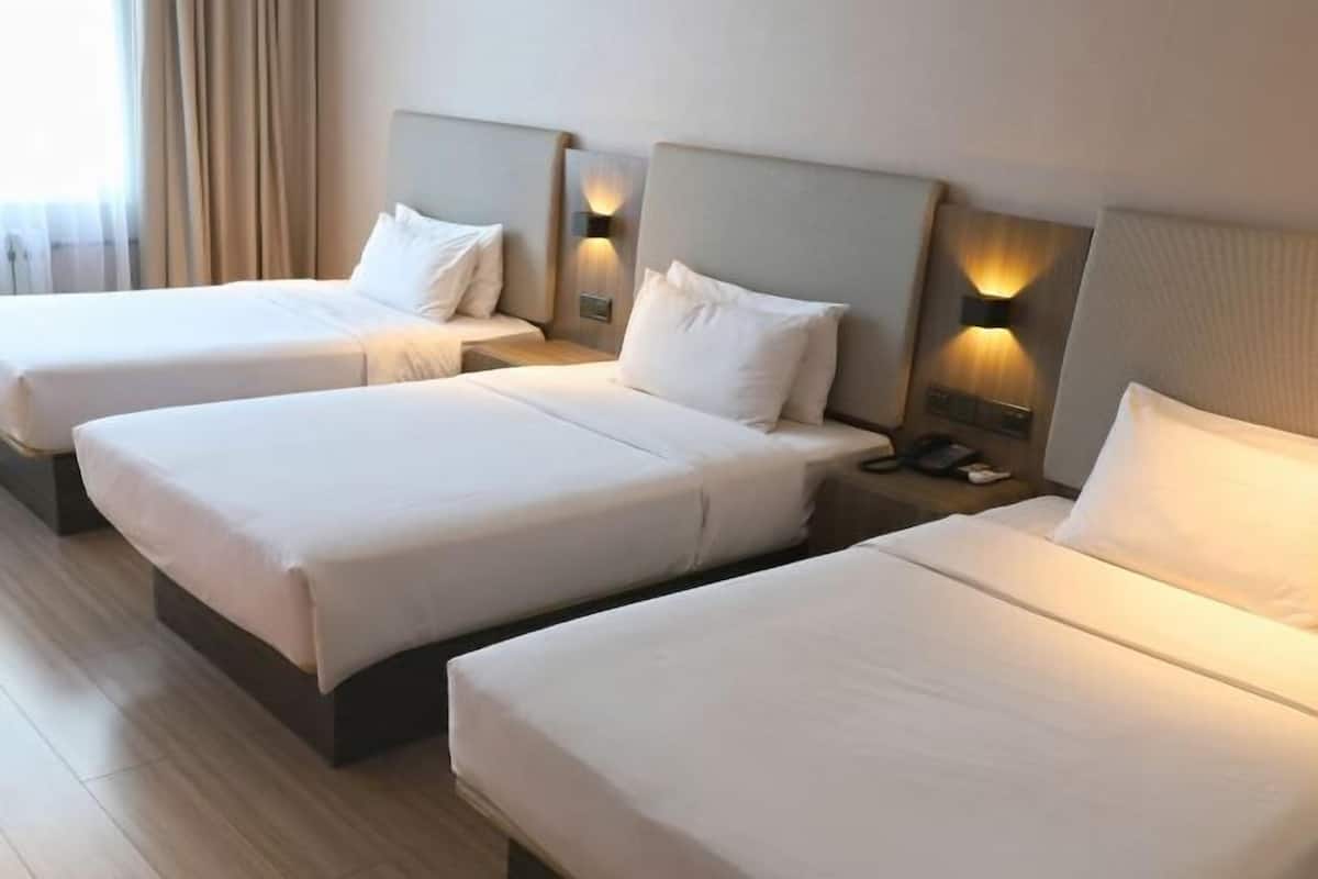 A hotel room with two single beds, each with a headboard and bedside tables.