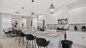 A modern kitchen with white cabinets, a granite countertop, and a central island with bar stools.
