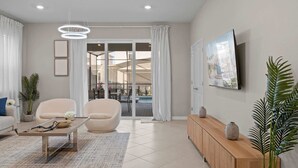 A modern living room with a sofa, armchair, coffee table, and a TV on the wall.