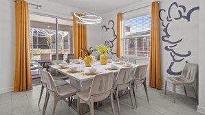 A dining room with a large table set for six, yellow curtains, and a wall mural. - Disney! Private Pool, Hot Tub, Game Room & Themed Bedrooms. Book Now! #CG788 (Orlando)