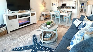 A living room with a TV, sofa, coffee table, and dining area.