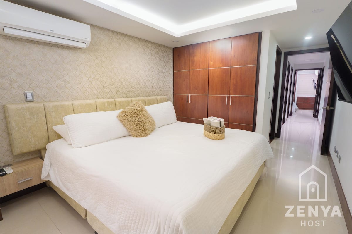 Ein Hotelzimmer mit Bett, Kleiderschrank, Nachttisch und Klimaanlage.