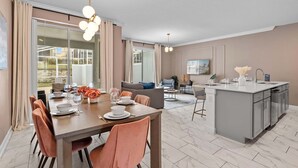 Une cuisine moderne dotée d’un îlot central, un coin repas avec une table et des chaises en bois, et un espace de détente avec un canapé et une table basse.