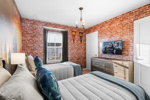 A bedroom with two beds, a TV, a brick wall, and a window with blinds. - Disney Getaway! Private Pool & Themed Bedrooms. Book Now! #CW78 (Orlando)