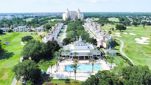 An aerial view of a resort with a central pool area, multiple buildings, and a golf course in the background. - Reunion resort (7 guests) near Disney (Kissimmee)