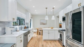 Una cocina moderna con muebles blancos, electrodomésticos de acero inoxidable y suelo de madera.