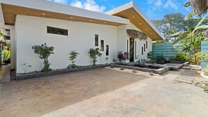 A modern house with a white exterior, a thatched roof, and a paved driveway. - Luxury Retreat Villa private Pool & BBQ by SPCR (Potrero)