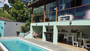 A poolside area with a pool, a hammock, outdoor seating, and a large window overlooking the pool.